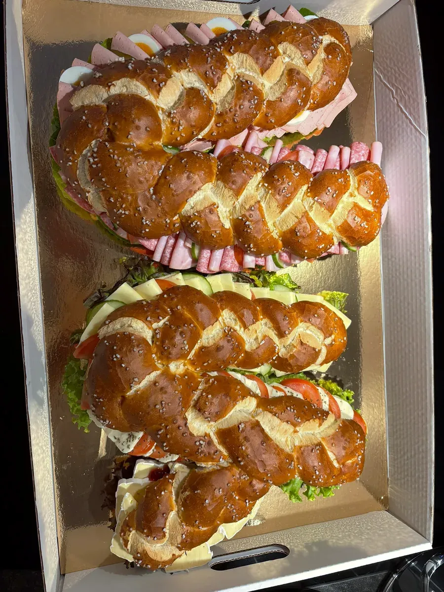 Vier gefüllte Laugenzöpfe im Karton, belegt mit Wurst, Käse, Tomate und Salat
